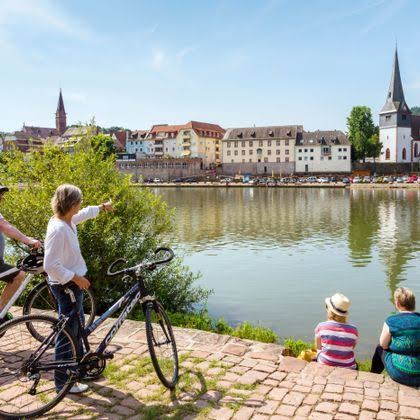 Cyclists on the riverfront promenade at Ladenburg with the old town across the water