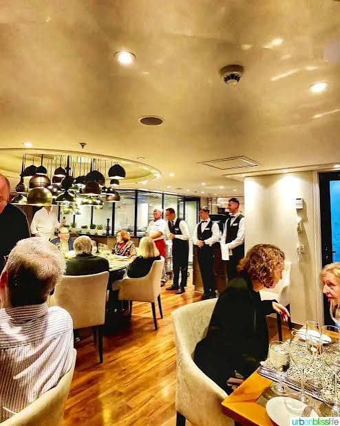 Guests seated for dinner in the ship's dining room with staff serving