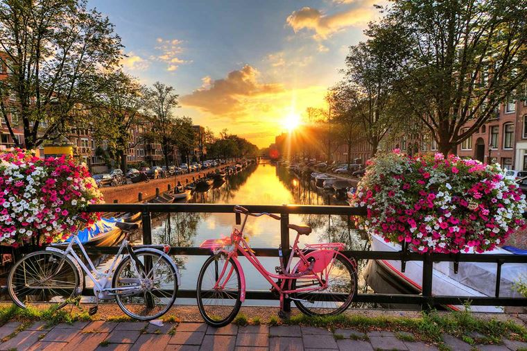 Amsterdam canal houses and bicycles beside the water at sunrise