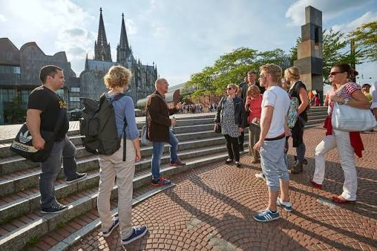 Guided walking tour group on the steps in front of Cologne Cathedral
