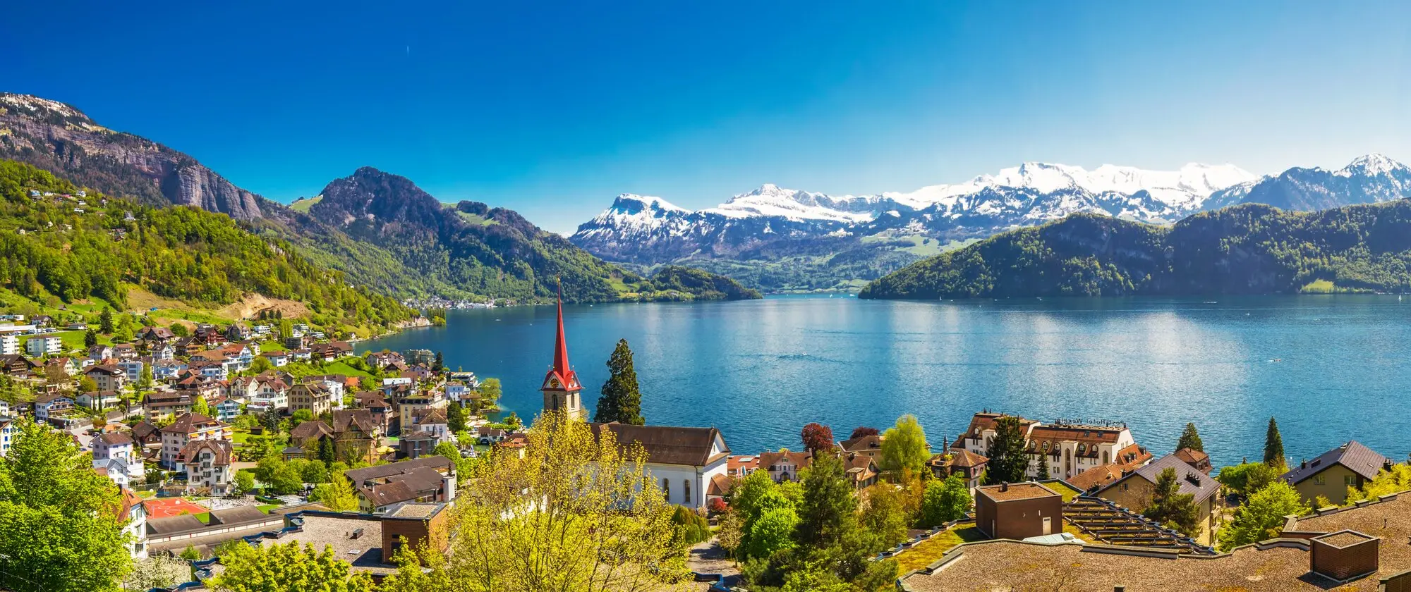 Lake Lucerne with snow capped Alps, the lakefront town, and a red church spire