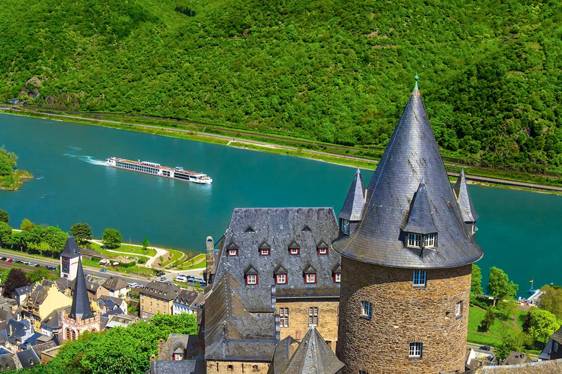 River cruise ship sailing the Rhine Gorge beneath vineyard hills and a castle tower