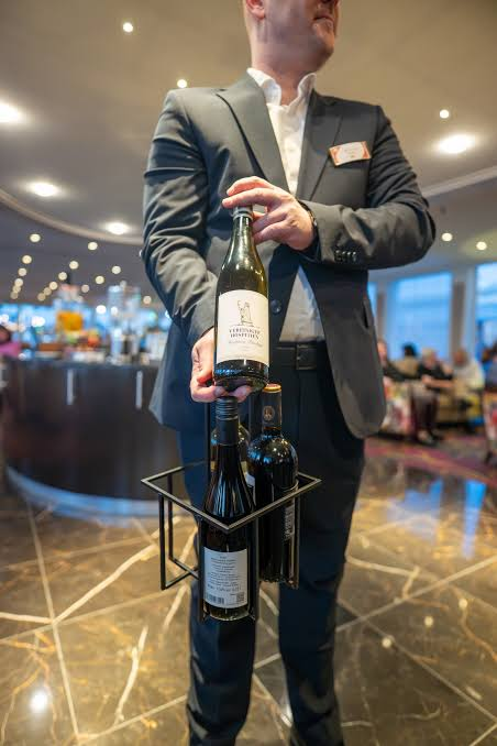 Crew member serving a selection of local wines in the lounge